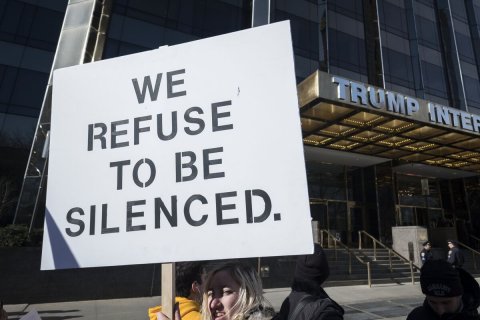 Office Building, Hat, Protest. Text: WE REFUSE TO BE SILENCED.