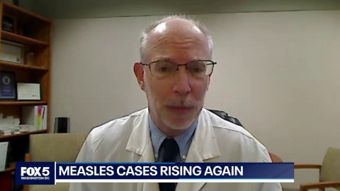 Coat, Man, Person. Text: MEASLES CASES RISING AGAIN FOX5