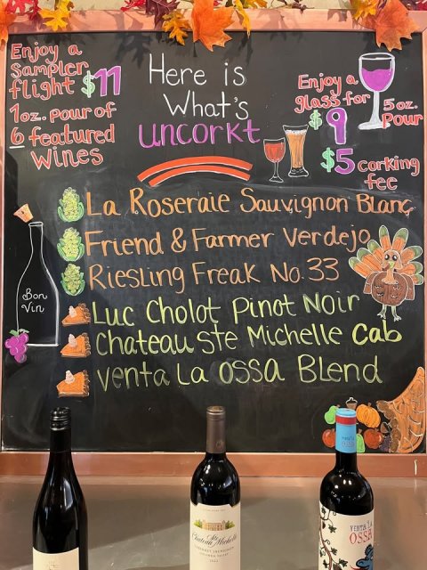 Blackboard, Alcohol, Beverage. Text: Enjoy a Sampler Here is flight $11 Enjoy a 1oz. Pour of What's glass for 5oz. 6 featured uncorkt Pour $5 corking Friend &amp; Farmer Verdejo Bon Riesling Freak No. 33 Vin Luc Cholot Pinot Noir Chateau ste Michelle Cab venta La ossa Blend