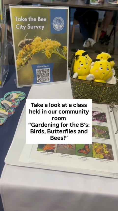 Book, QR Code, Person. Text: Take the Bee City Survey Scan Here Take a look at a class held in our community room "Gardening for the B's: - - Birds, Butterflies and Bees!" Monarch - - - - -