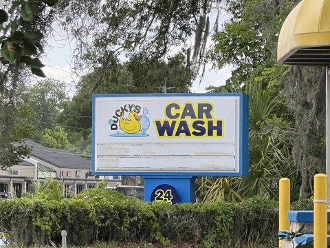 Advertisement, Car, Vegetation. Text: CAR WASH 24