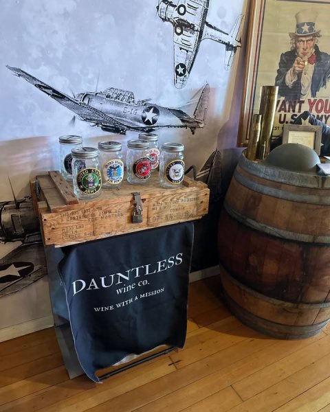 Person, Airplane, Factory. Text: ANT YOU U.S EST DAUNTLESS wine CO. WINE WITH A MISSION