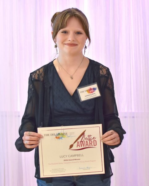 Blouse, Person, Woman. Text: Bettie AWARD LUCY CAMPBELL 2026 Award Winner